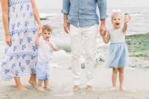 Young children smile and wave during a beach family photo session held in Laguna Beach, California by a local photographer.