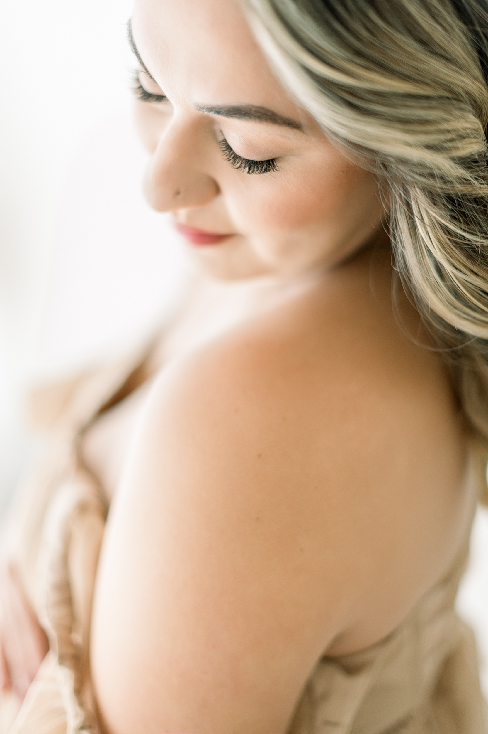 A closeup of a mom to be's shoulder as she smiles at it in a studio after a 3d ultrasound in orange county