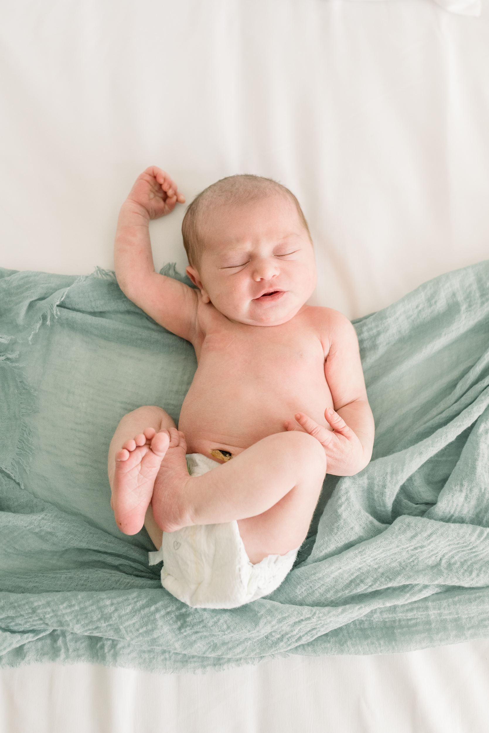 A newborn baby lays on a bed in only a diaper before finding a diaper service in orange county