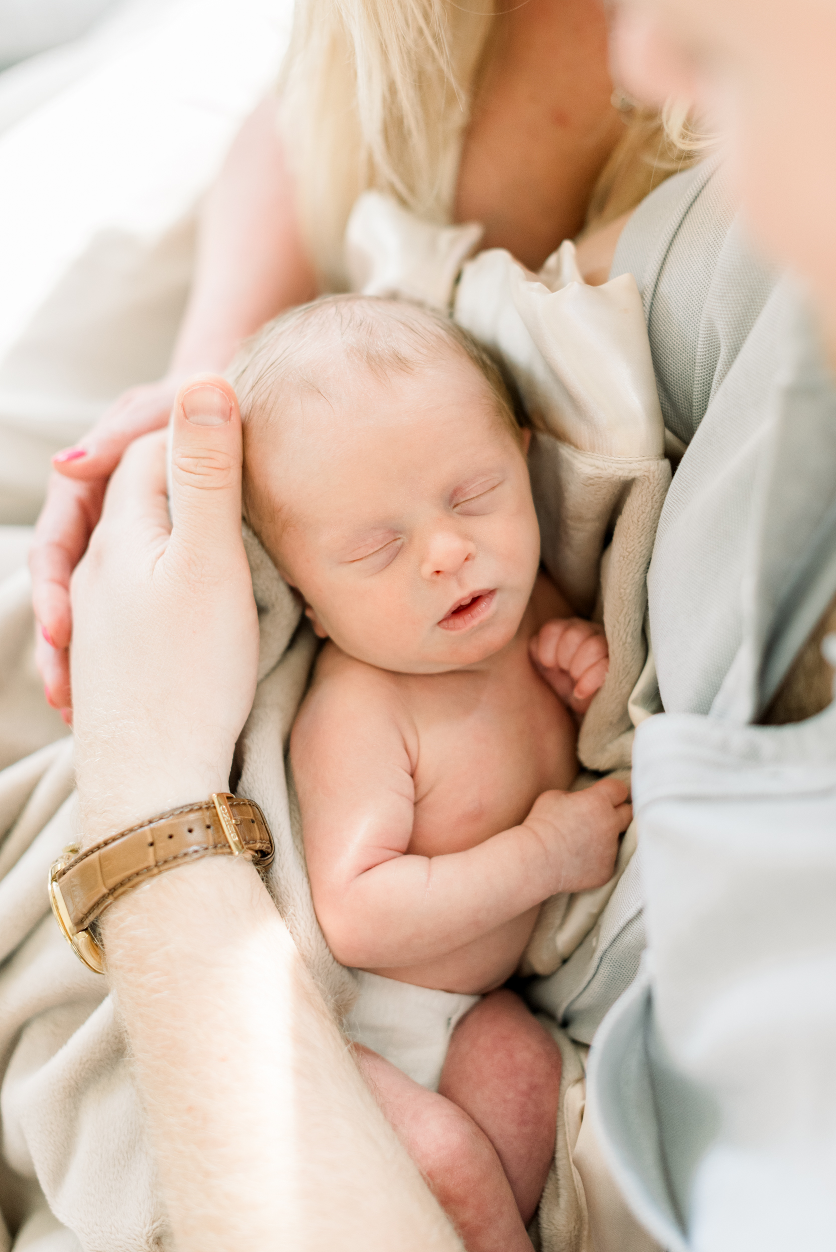 A look down to a newborn baby sleeping in dad's arms on a couch before visiting a pediatric dentist in orange county