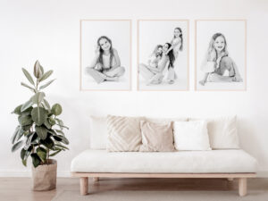 Three images of children's personality portraits hang on a wall in black and white along with a photo in the center of them with their mom having fun.