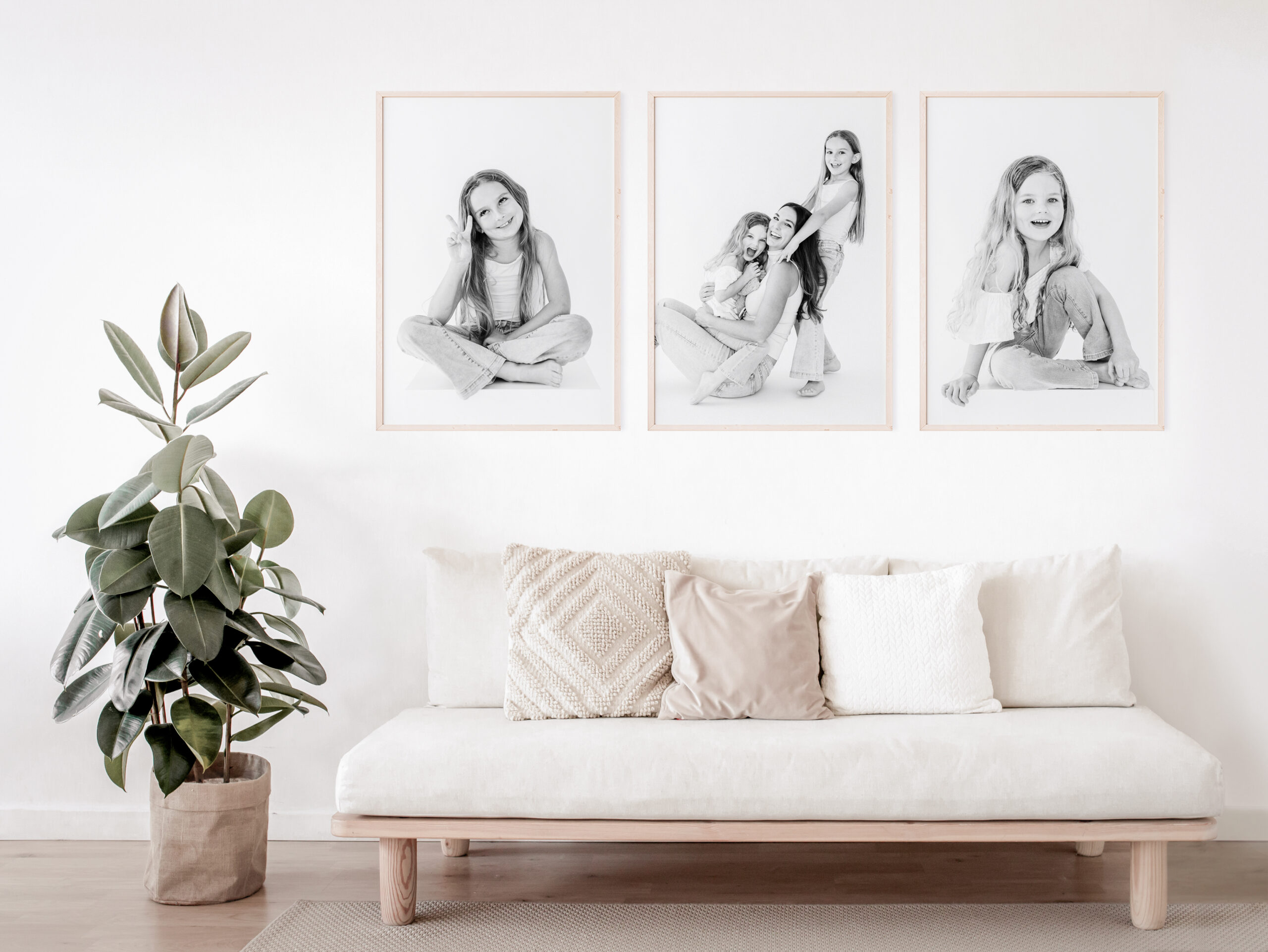 Three images of children's personality portraits hang on a wall in black and white along with a photo in the center of them with their mom having fun.