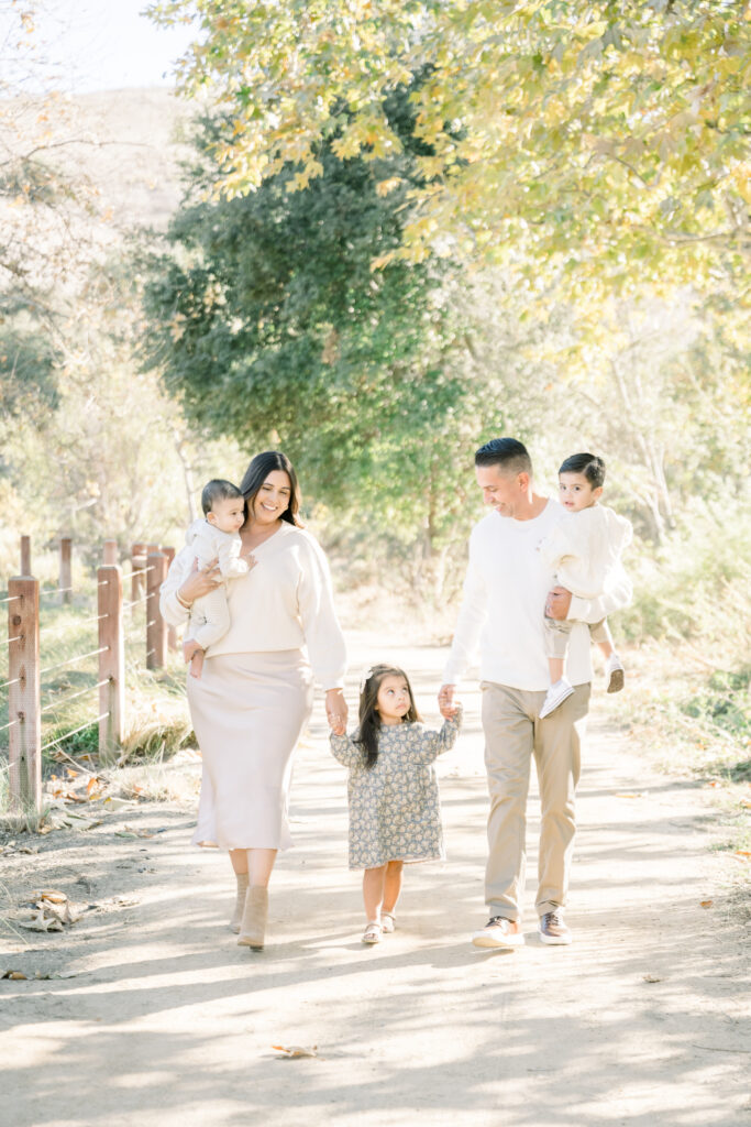 Family smiles as they walk among fall colors for a photoshoot with Orange County Mini Sessions photographer Amy Captures Love