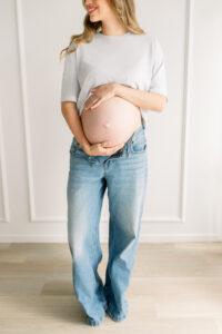 wearing wide leg jeans, a tee-shirt, and belly hanging out at a maternity photoshoot with Amy Captures Love in Orange County, California