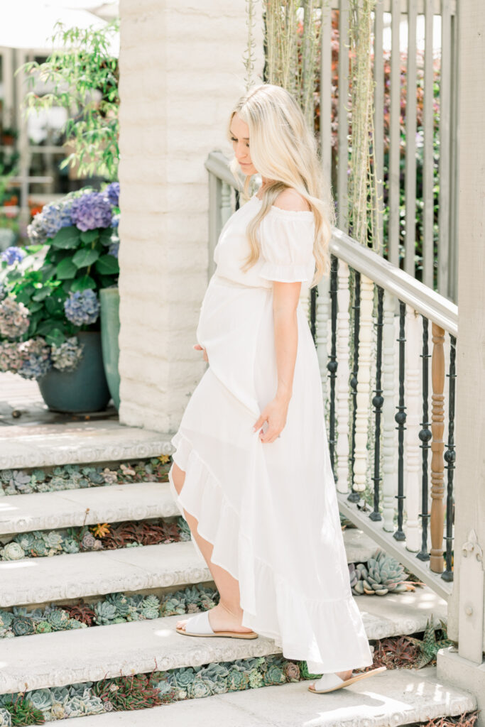 Pregnant woman looks down as she walks through Sherman Gardens. Shot with Amy Captures Love in Corona Del Mar, California.