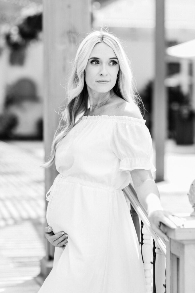 Pregnant woman looking back as she contemplates when to schedule her maternity session. Shot with Amy Captures Love at Sherman Gardens in Corona Del Mar, California.